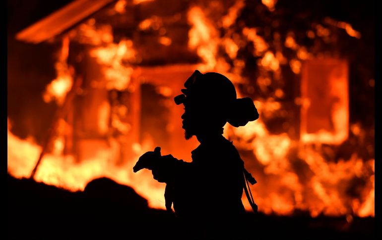 Un bombero vigila las llamas mientras una casa arde en la región de vinos de Napa, California. Varios incendios azotan la entidad. AFP/J. Edelson