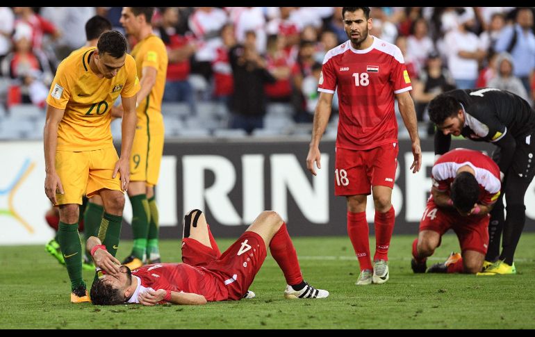 Trent Sainsbury (i), de la Selección de Australia, consuela a Jehad Al Baour (2 i), de Siria, tras el partido  en Sídney en que los locales ganaron y dejaron a Siria fuera del Mundial de 2018. AFP/W. West