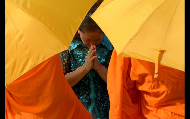 Una mujer ora con monjes budistas en una calle de Phnom Penh, Camboya. AFP/T. Chhin Sothy