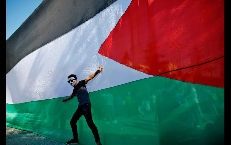 Un palestino posa frente a su bandera nacional durante celebraciones en la Ciudad de Gaza, luego de que facciones palestinas de Hamas y Fatah firmaron en El Cairo un acuerdo de reconciliación que termina una década de luchas. AFP/ M. Abed