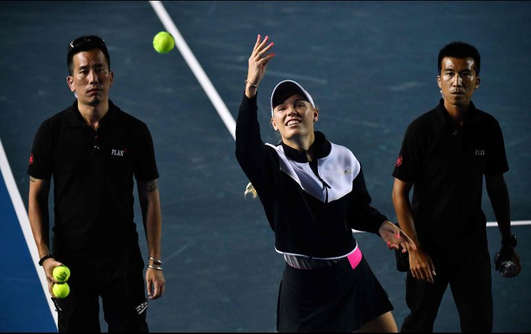 Caroline Wozniacki lanza pelotas al público después de disuclparse por no poder continuar. AFP/A. Wallace