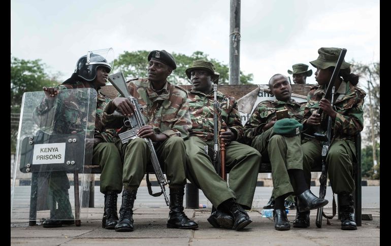 NAIROBI, KENIA.- Oficiales de policía descansan mientras se organiza una manifestación frente a la Comisión Electoral debido a la incertidumbre que reina sobre la elección presidencial. AFP / Y. Chiba