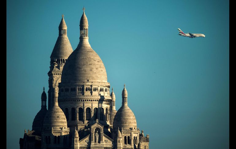 Un avión pasa detrás de la cúpula de la Basílica del Sagrado Corazón en el barrio de Montmartre en París, Francia. AFP / O, Morín