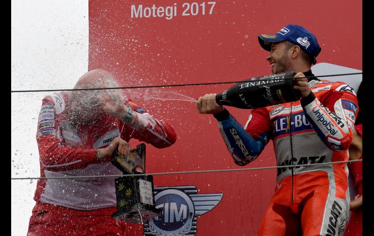Andrea Dovizioso (d), de Ducati, rocía champaña al oficial de su equipo, tras ganar el Gran Premio de Moto GP de Japón en el circuito en Motegi. AFP/T. Kitamura