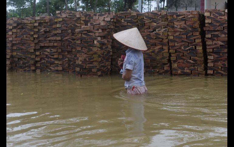 Una mujer camina por una vía inundada en el distrito Chuong My, en Hanoi. AFP/H. Dinh Nam
