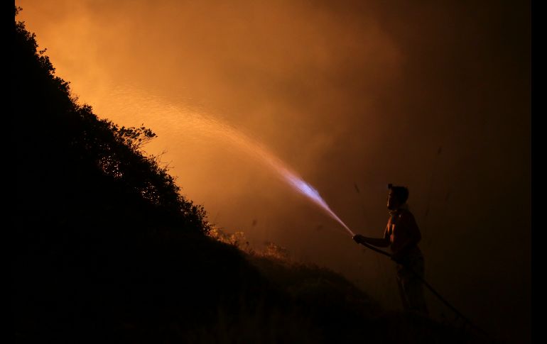 Un voluntario usa una manguera común para combatir un incendio forestal en Obidos, Portugal. Al menos 36 personas han muerto en los incendios registrados desde el domingo en el norte y el centro del país. AP/A. Franca