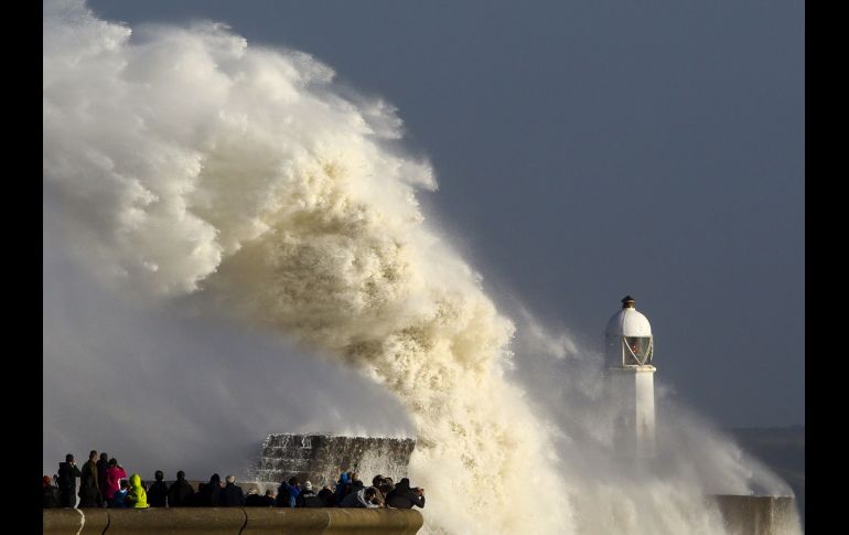 Olas golpean una barrera y un faro en Porthcawl, Gales, por los efectos de la tormenta 
