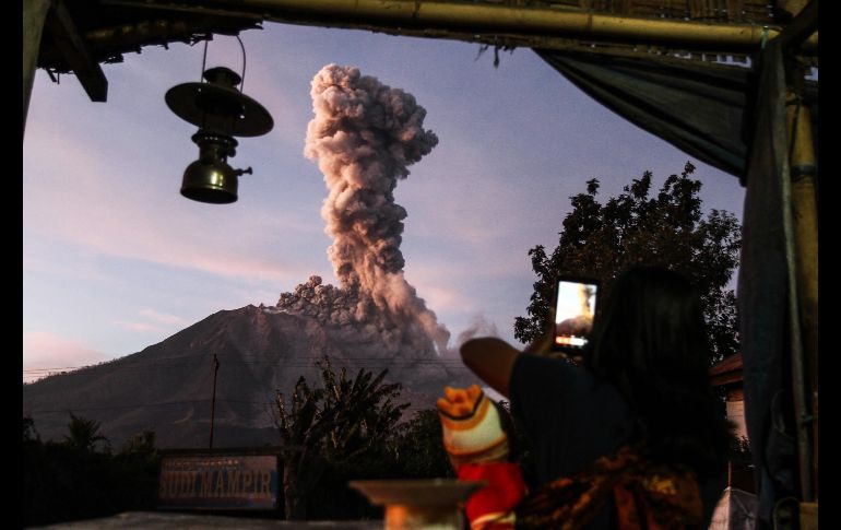 Una persona toma una foto del volcán Sinabung mientras arroja ceniza en Karo, Indonesia. AFP/I.  Damanik