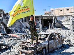 Un miembro de las Fuerzas Democráticas Sirias (SDF), sostiene su bandera en la icónica plaza de Al-Naim, en Al Raqa. AFP/B. Kilic
