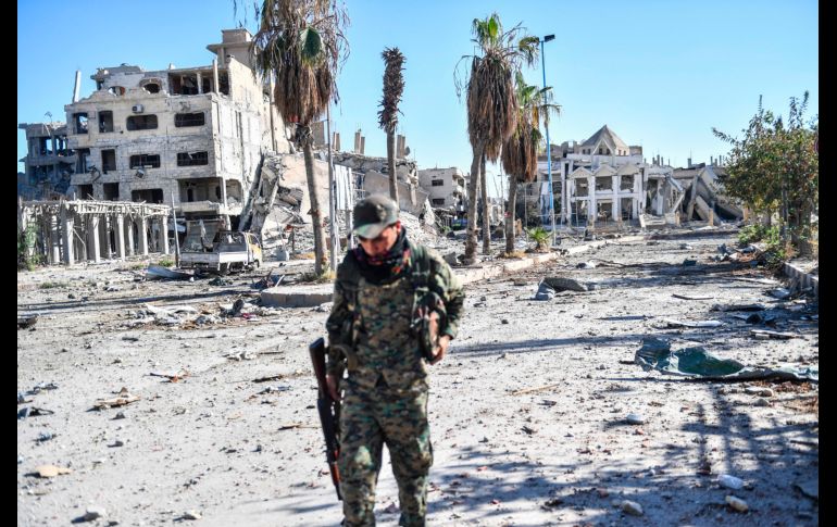 Un integrante de las Fuerzas Democráticas Sirias camina en una calle de Raqa. Los combatientes de las Fuerzas han retomado el control de los bastiones del Estado Islámico tras una ofensiva de más de cuatro meses. AFP/B. Kilic