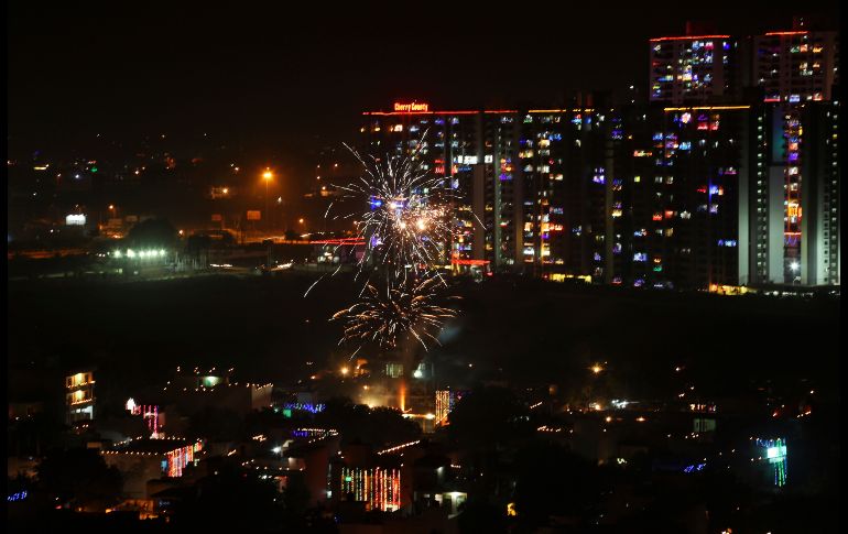 Edificios residenciales se ven decorados con luces de colores mientras estallan fuegos artificiales, durante el Festival 