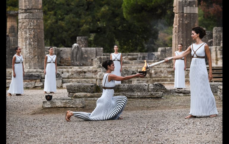 La actriz griega Katerina Lechou (d) enciende la antorcha olímpica en las ruinas de la antigua Olimpia,  durante la ceremonia de encendido de la llama de los Juegos de Invierno PyeongChang 2018. AFP/A. Messinis