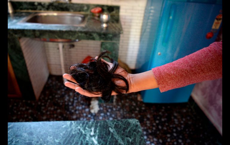 Una mujer muestra el cabello que cortaron a su familiar. AFP/T. Mustafa