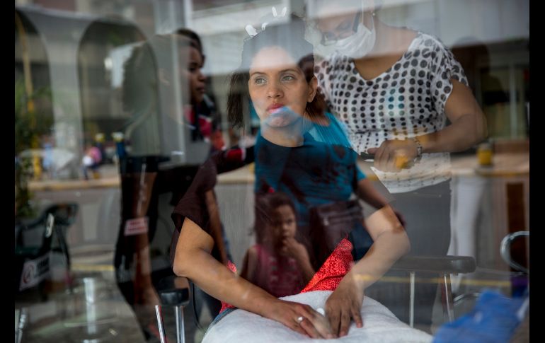 Dayanara Monsalve se ve a través de una venta mientras una estilista termina de hidratar su cabello en un el centro de Caracas, Venezuela. AP/R. Abd