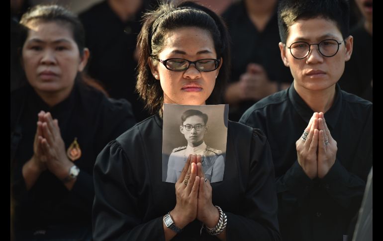 Una mujer con una imagen del fallecido rey tailandés Bhumibol Adulyadej asiste al funeral del  monarca en Bangkok. Bhumibol  fue incinerado hoy, a un año de su muerte. AFP/Y. Aung Thu