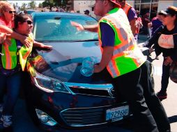 Una mujer golpeó el capó del auto al ser empujada por el vehículo y otro manifestante se subió al auto en movimiento. AP / A. Mendoza
