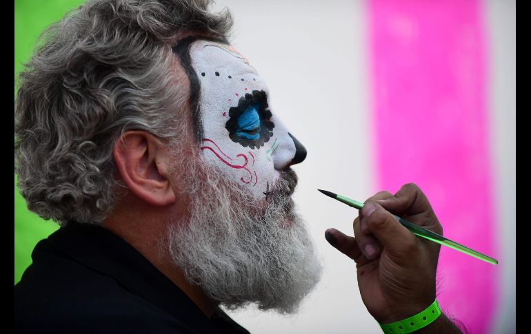Un hombre que forma parte de los animadores del espectáculo, es maquillado para convertirse en calabera. AFP / P. Pardo