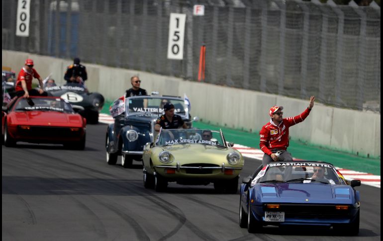 El alemán Sebastian Vettel (d), de Ferrari, pasa en el desfile de autos antiguos.