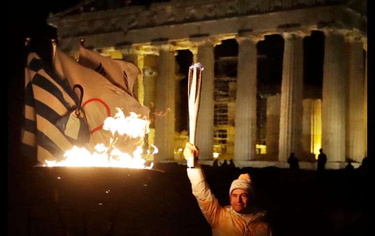 Dimosthenis Tampakos, gimnasta griego y medallista olímpico, enciende el pebetero con la llama olímpica frente al templo del Partenón en Atenas. La llama se dirige a Pyeongchang, Corea del Sur, que albergará los Juegos de Invierno. AP/T. Stavrakis