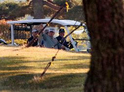 Donald Trump (c) saluda a los medios mientras se traslada con Shinzo Abe (d) tras el juego de golf. AFP/J. Watson