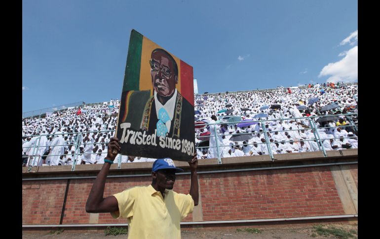 Un seguidor del presidente de Zimbabwe, Robert Mugabe, sostiene un retrato suyo durante una reunión de iglesias de diferentes credos en Harare. AP/T. Mukwazhi