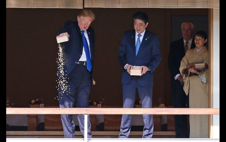 El presidente Donald Trump y el primer ministro japonés Shinzo Abe se tomaron una pausa de las ceremonias oficiales para alimentar carpas en un estanque de koi en Tokio. Trump concluyó volteando la caja para arrojar el resto del alimento. AP/T. Hanai