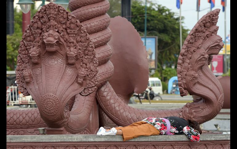 Una mujer duerme cerca de estatuas de naga (serpiente mítica) en un parque de Phnom Penh, en Camboya. AFP/T. Chhin