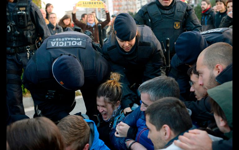 Mossos d'Esquadra, policías regionales, jalan a manifestantes que bloquean una calle en Barcelona. AFP/J. Lago