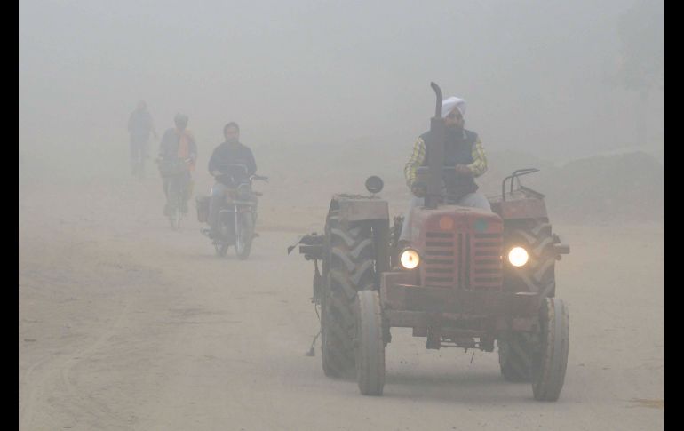 Un hombre conduce un tractor entre una capa de contaminación que envuelve la ciudad india de Amritsar, debido a una conjunción de superficies agrícolas quemadas y de emisiones urbanas.