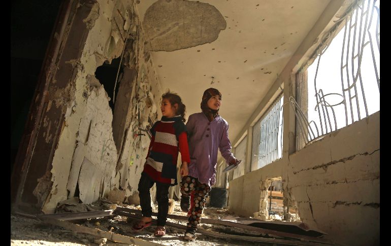 Niños recorren su escuela dañada en Saqba, zona de combatientes rebeldes, tras bombardeos aéreos por parte de fuerzas del gobierno sirio.  AFP/A. Almohibany