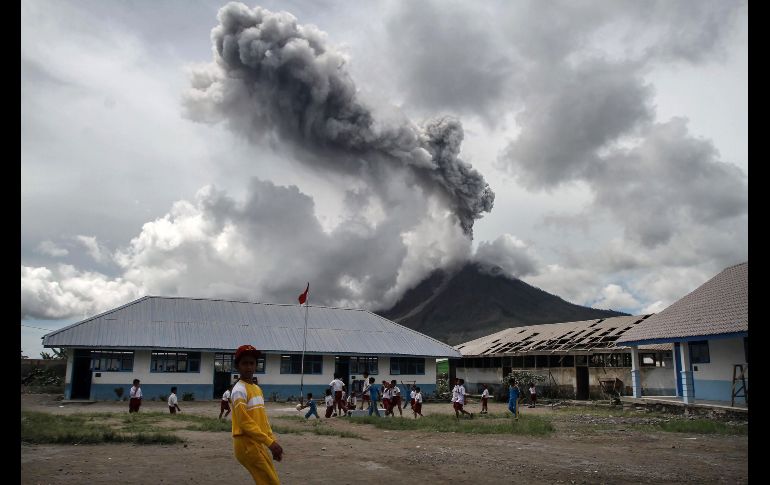 Niños juegan en una escuela mientras el volcán Sinabung arroja una columna de humo en Karo, Indonesia. AFP/I. Damanik