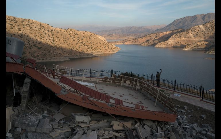 Un hombre toma una foto de un inmueble dañado cerca del lago Darbandikhan.