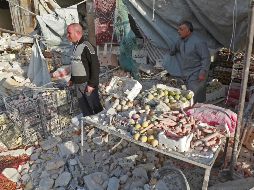 Dos hombres lloran junto a varias cajas de verduras llenas de polvo. AFP/E. Al Rifai
