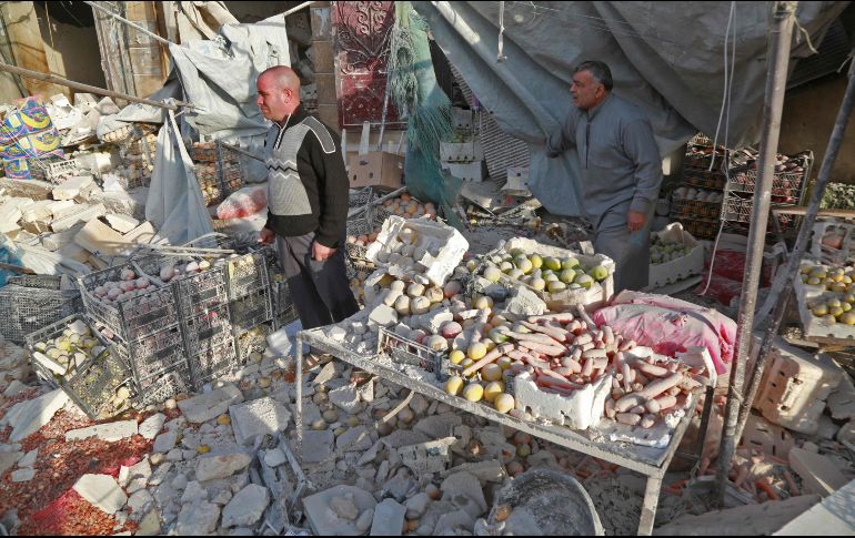 Dos hombres lloran junto a varias cajas de verduras llenas de polvo. AFP/E. Al Rifai