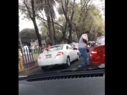 En un breve video subido a redes sociales, se observa cuando el sujeto se encuentra de pie junto a la ventana del conductor de un auto rojo. TWITTER / @gabogrizzly