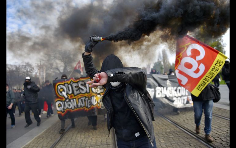 Un manifestante sostiene una bengala en Nantes, Francia, durante una protesta nacional en contra de las reformas económica y social del gobierno. AFP/L. Venance