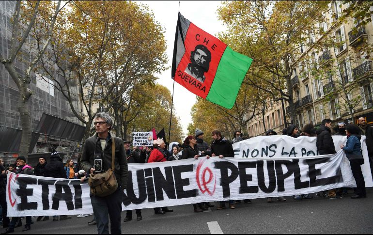Manifestantes avanzan detrás de una manta donde se lee: 'El Estado arruina a las personas'. AFP/C. Archambault