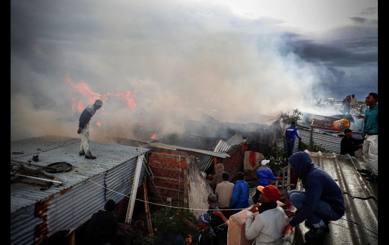 Residentes de un barrio de Ciudad del Cabo, Sudáfrica, intentan sofocar las llamas de un fuerte incendio. La zona es particularmente susceptible a incendios dado el difícil acceso de los bomberos y el hacinamiento. EFE/ N. Bothma