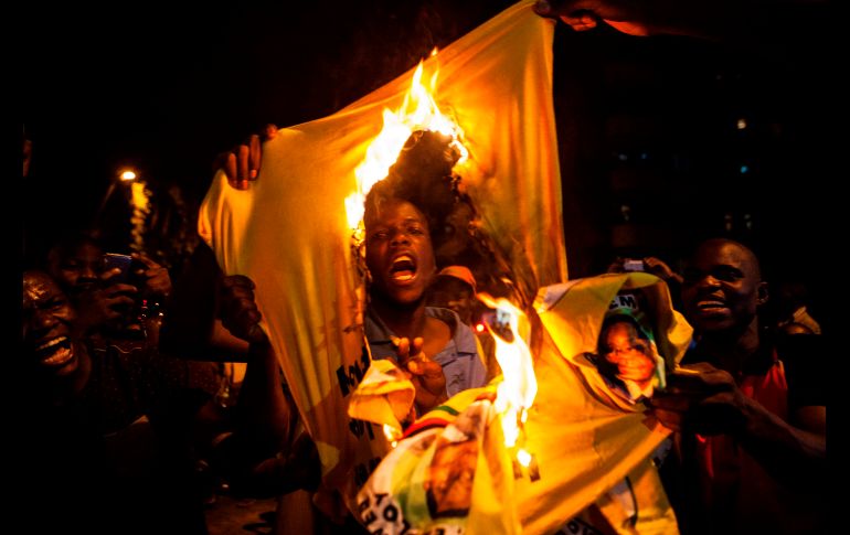 Un grupo de jóvenes queman una playera con la foto y el nombre de Mugabe. AFP / W. De Wet