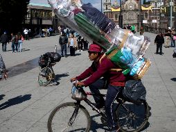 Un muchacho carga dos figuras de la Virgen María mientras pasa en su bicicleta afuera de la Basílica de Guadalupe. AP / E. Verdugo