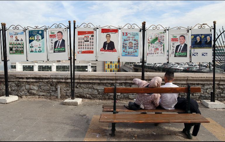 Una pareja descansa en un banco frente a varios carteles electorales en Argel. EFE/M. Messara