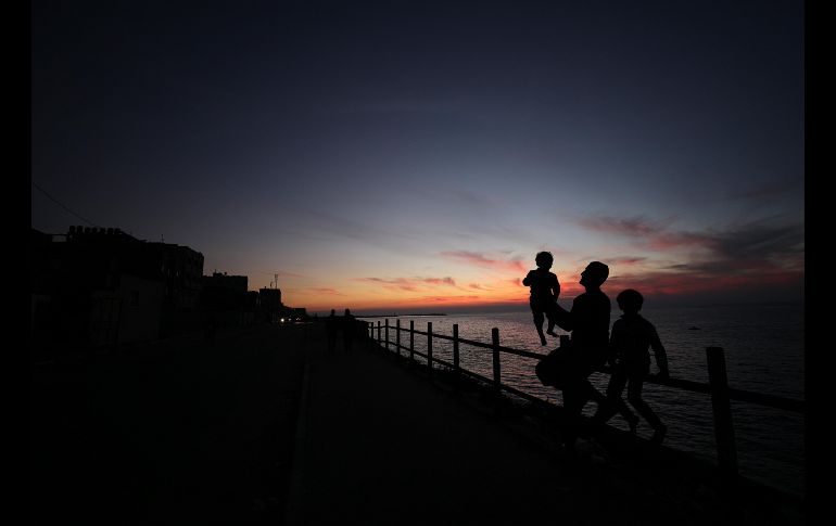 Un padre y sus hijos contemplan la puesta de sol cerca de una playa, en el norte de la Franja de Gaza. EFE/ M. Saber
