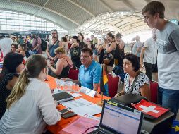 Turistas escuchan información sobre sus vuelos tras la erupción del volcán Agung, en el aeropuerto Ngurah Rai. EFE/G. Surya