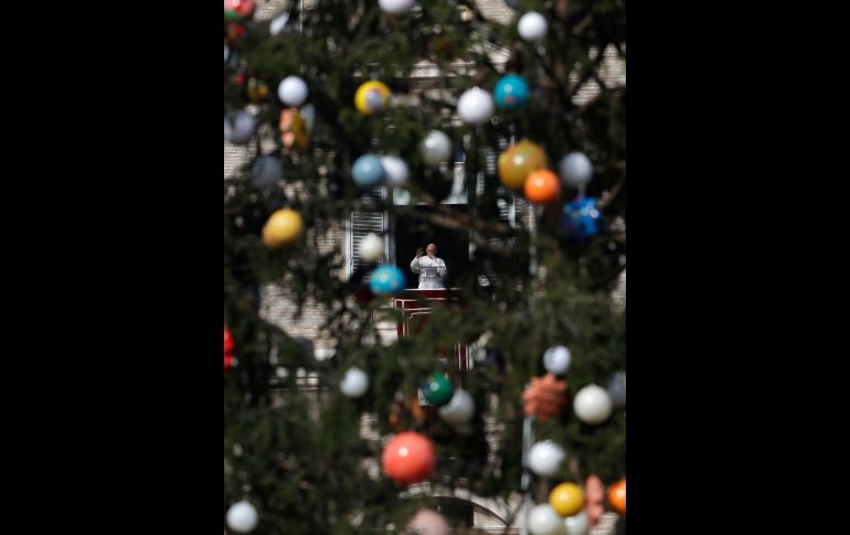 Enmarcado por un árbol de Navidad, el Papa Francisco se ve mientras saluda a los fieles católicos, durante el rezo del Angelus en la plaza de San Pedro, en el Vaticano. AP/A. Tarantino