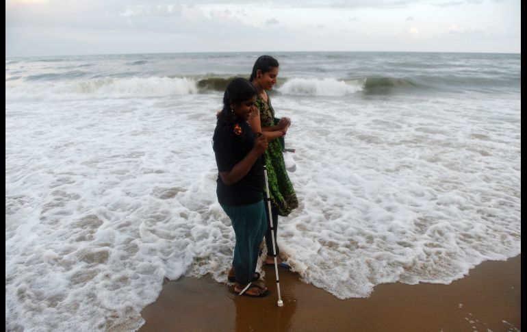 Una voluntaria ayuda a una joven con discapacidad visual a caminar por una playa en Chennai, India. AFP/A. Sankar