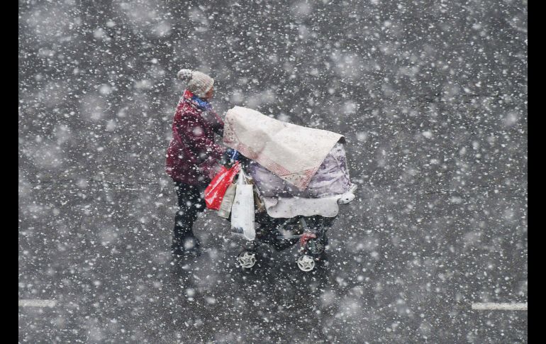 Una mujer empuja una carriola durante una nevada en la ciudad china de Yantai. AFP
