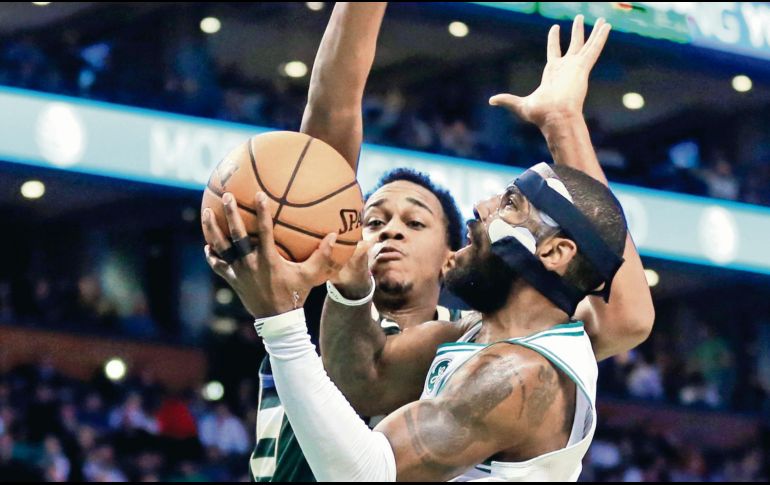 Kyrie Irving. La estrella de los Celtics intenta encestar ante la marca de John Henson, durante el juego de ayer entre Boston y los Bucks de Milwaukee. AFP