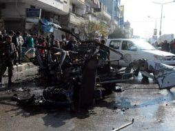 Transeúntes rodean varios vehículos destruidos tras la explosión. EFE/SANÁ