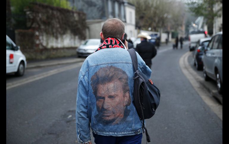 Un fan del artista Johnny Hallyday, con una chaqueta con su retrato, se dirige a la vivienda del cantante francés, tras conocerse su fallecimiento, en Marnes-la-Coquette, Francia. EFE/ Y. Valat