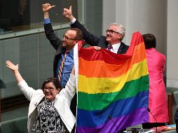Los diputados Cathy McGowan (i), Adam Brandt (c) y Andrew Wilkie (d) celebran la aprobación del matrimonio entre personas del mismo sexo en el Parlamento en Canberra. EFE/M. Tsikas